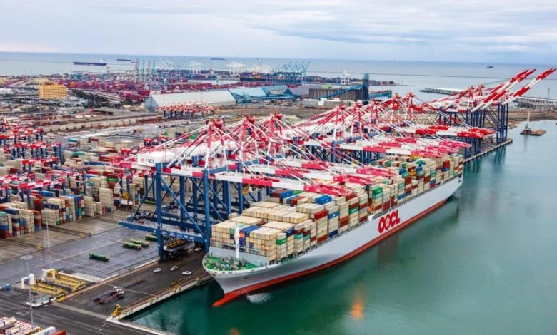 Clear news photograph of an OOCL container vessel berthed at a port terminal, directly relevant to US-China shipping fee regulations mentioned in the article.