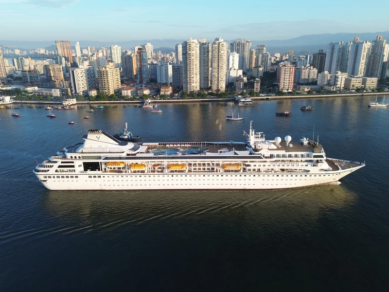 A real photograph showing the residential cruise ship Villa Vie Odyssey sailing off a city coastline, directly relevant to the article discussing the vessel.