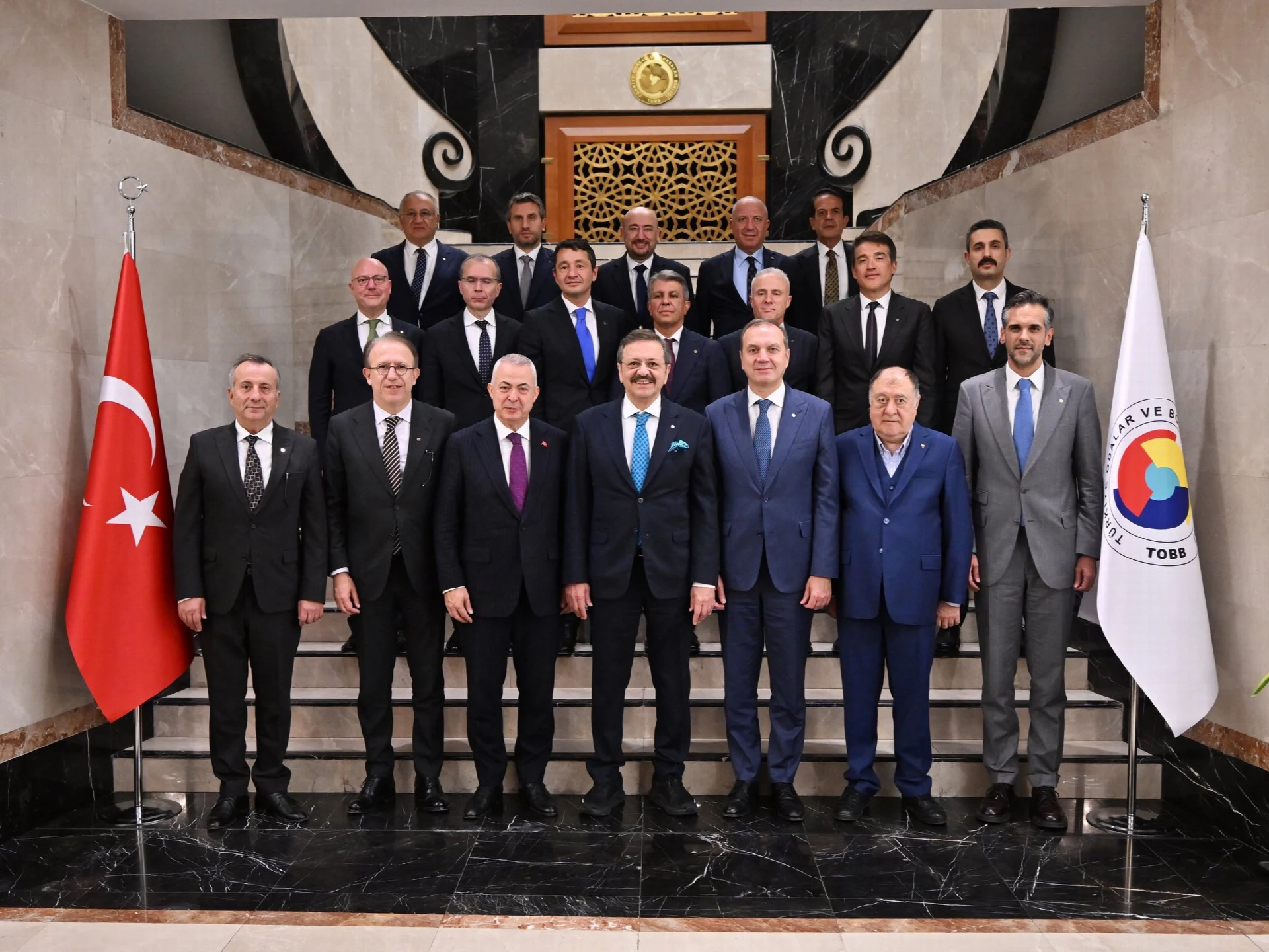 The photo shows the İMEAK Chamber of Shipping delegation posing with TOBB President M. Rifat Hisarcıklıoğlu inside the TOBB headquarters, flanked by the Turkish flag and the TOBB flag. It directly depicts the official visit described in the article.